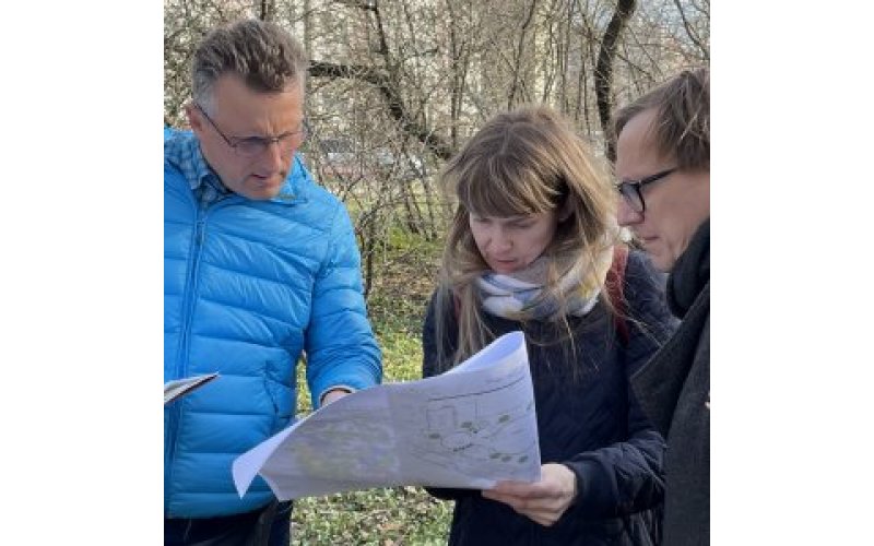 Three people outside looking at a map