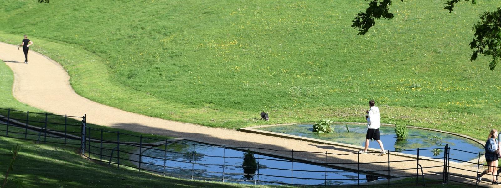 people running by a stream long footpath meandering through greenspace