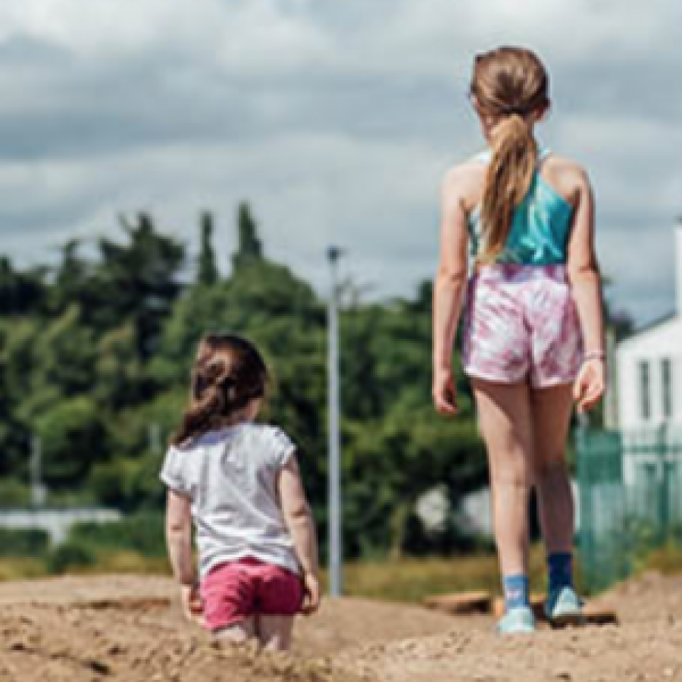 The backs of two young girls walking on sand