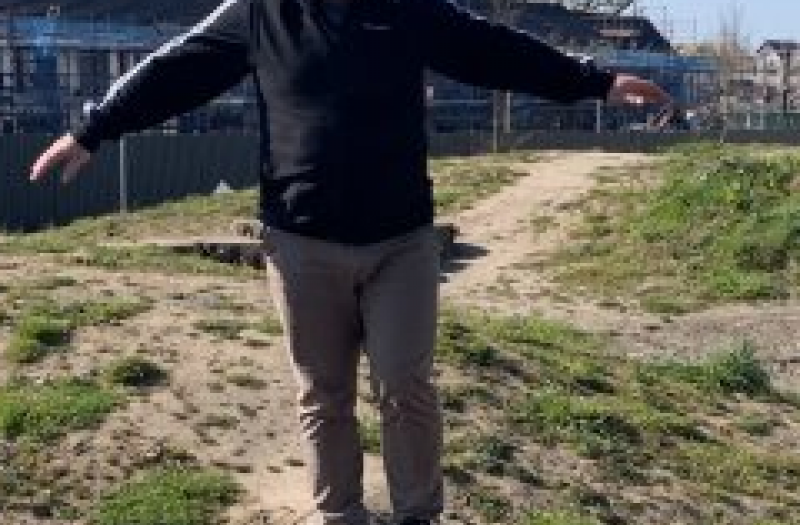 Older man balancing on wooden beam outside