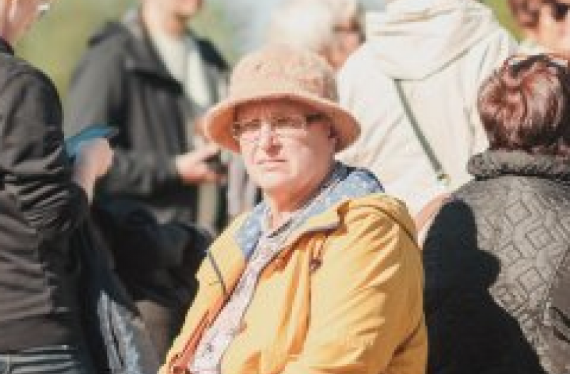 Person in hat facing camera with the backs of other people behind them