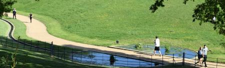 people running by a stream long footpath meandering through greenspace