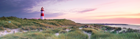 lighthouse on sand dunes at sunset
