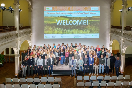 european panel event - everyone stood on stage with "Welcome" banner behind them