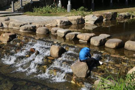 man-sits-rock-near-waterfall