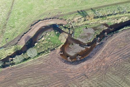Aerial view of a river going through a field