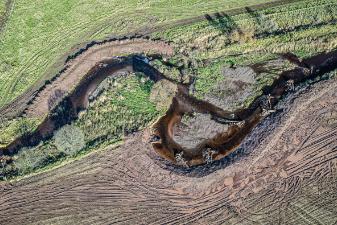 meandering river birdeye view - green fields surrounding