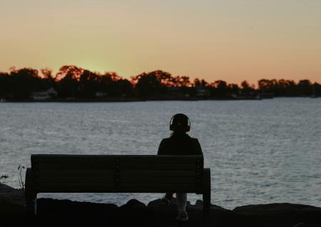 A person sitting on a bench on a sunset by a river