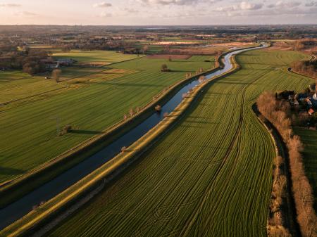 Landscape view of human made river going through a field