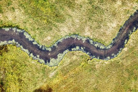 Aerial view of a river going through a field