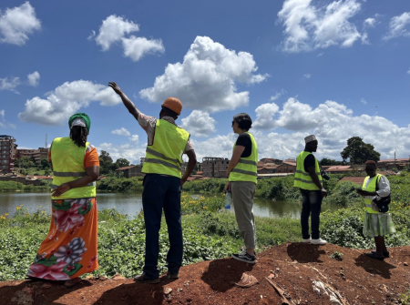 5 people in high vis jackets standing on brown mound with blue sky