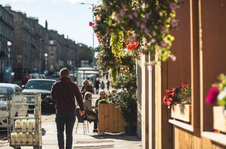 Edinburgh, scotland, uk a Man Walking Down a Colorful Street With a Flower-Filled Cart scottish architecture travel