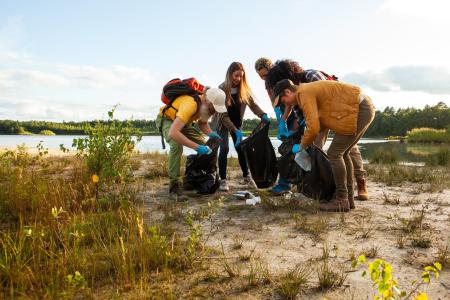 people litter picking - blue sky and sandy patchy dry grass surrounding them