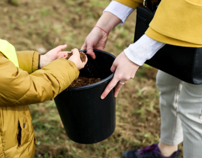 The picture shows a child taking soil out of a bucket