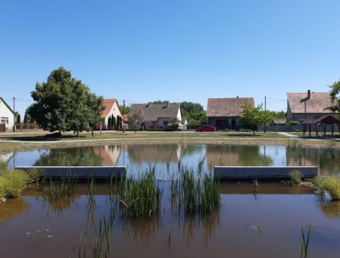 A water storage pond with housing behind it.
