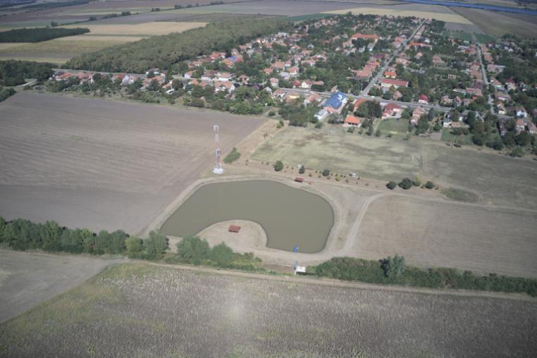 A water retention pond in a ploughed field.