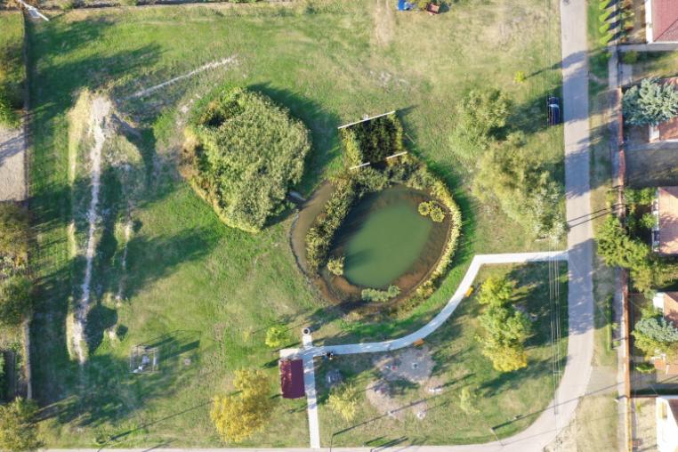 Aerial image of a small water retention pond near to housing.